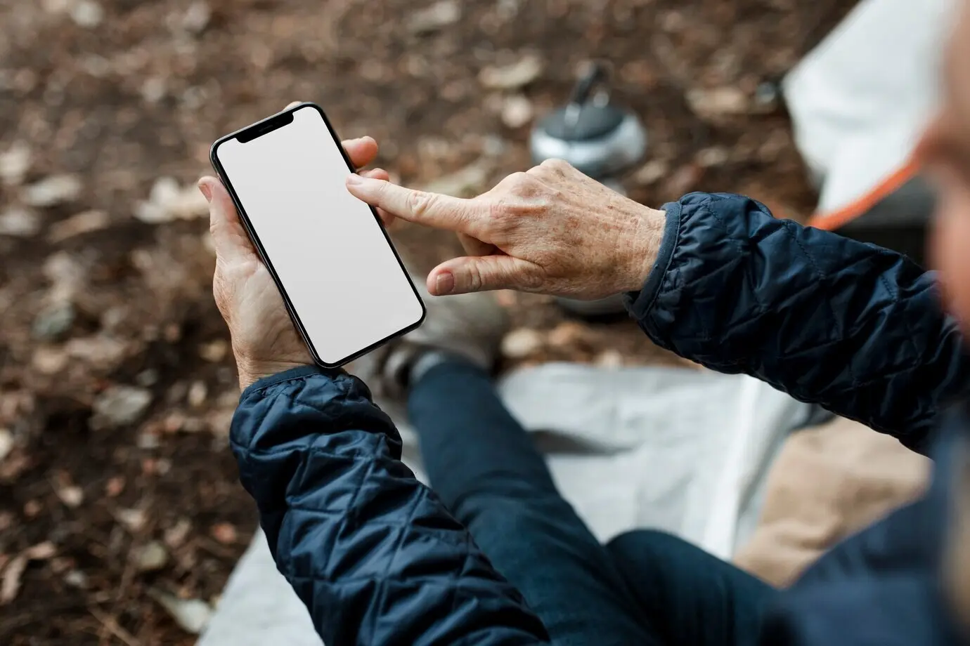 Elderly woman holding a smartphone with a white screen